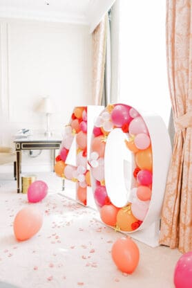 A balloon structure of 40 with coral, pink and orange balloons in a hotel room