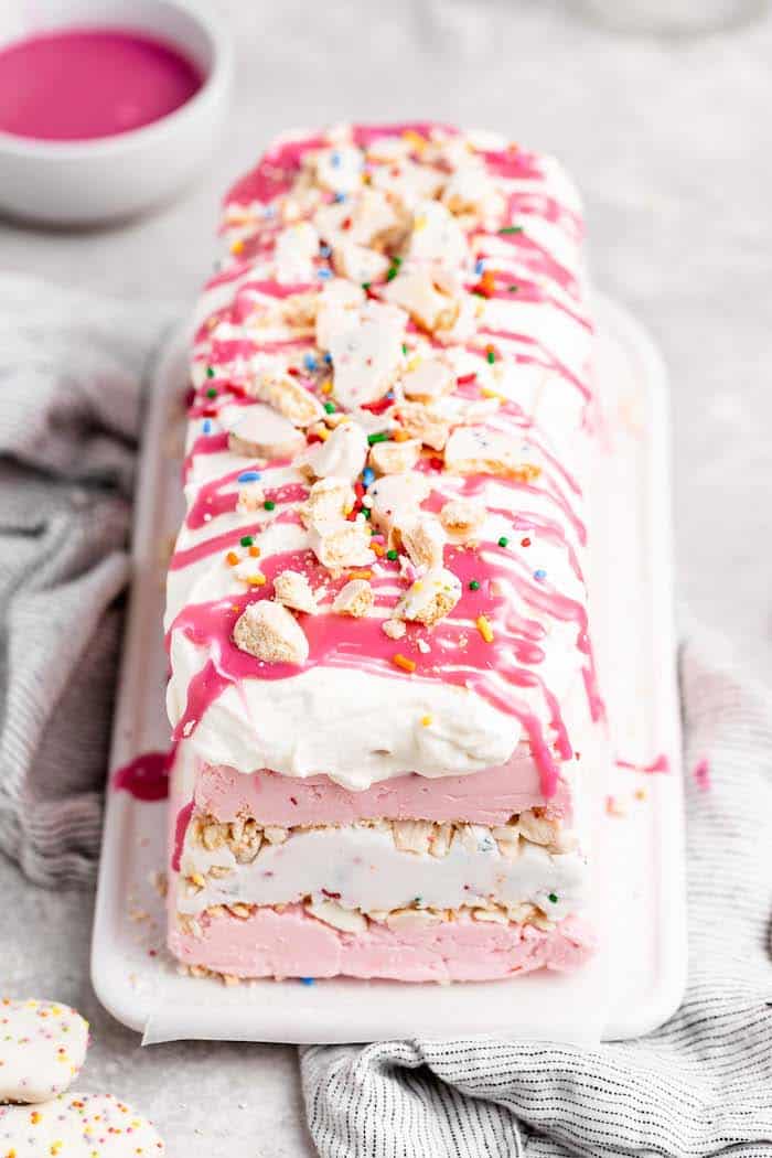 A pink animal cookie icebox cake with pink ganache dripping down sides