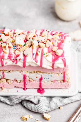 A close up of an ice cream cake with strawberry ice cream and cookies on top