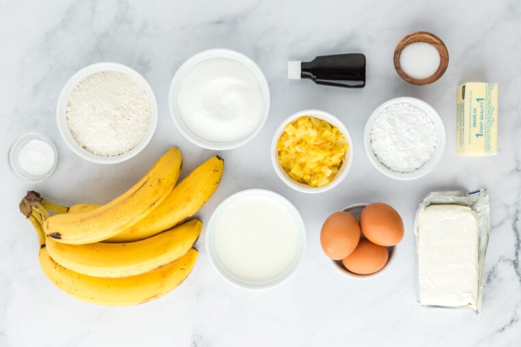 Bananas and cake ingredients in white bowls on white countertop