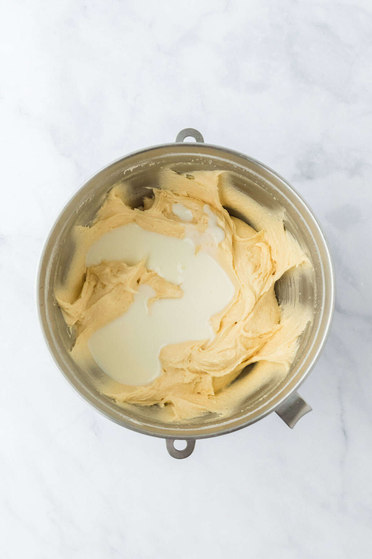 Buttermilk being added to cake with banana recipe on white countertop