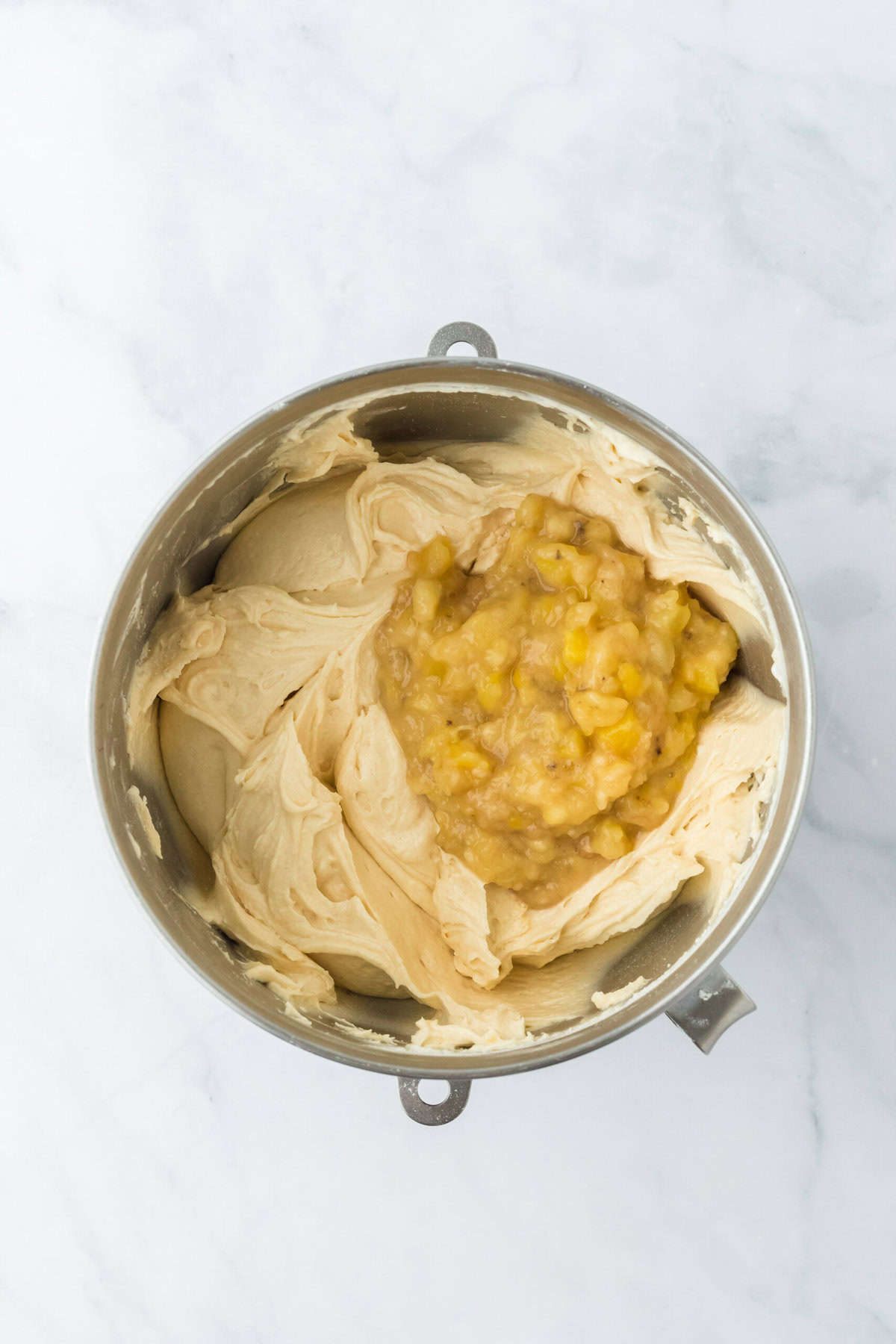 Banana and pineapple being added to cake with banana recipe on white background