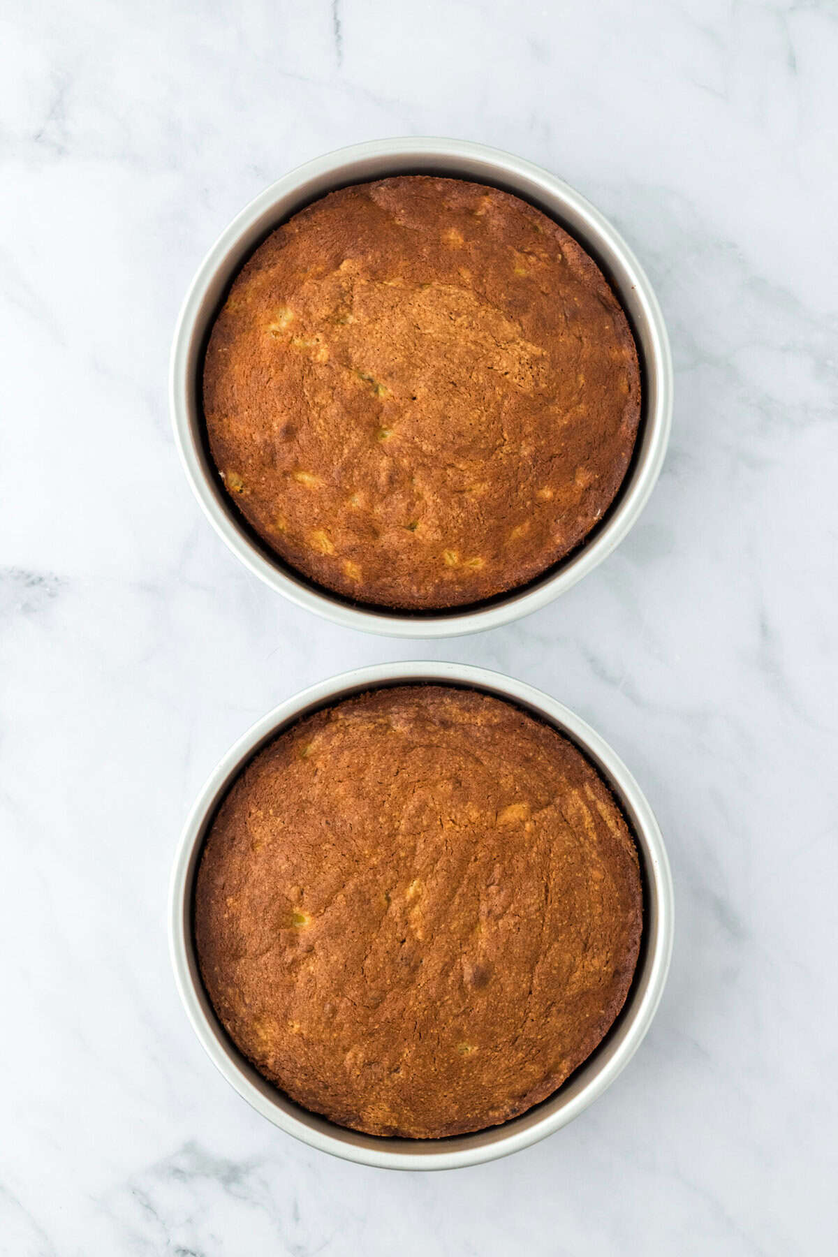 Two baked layers of banana cake recipe on white countertop