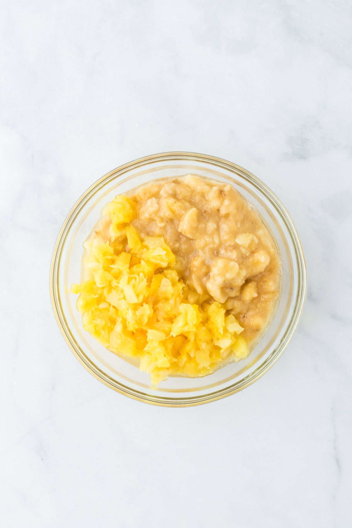 Pineapple and banana together in a glass bowl on white background