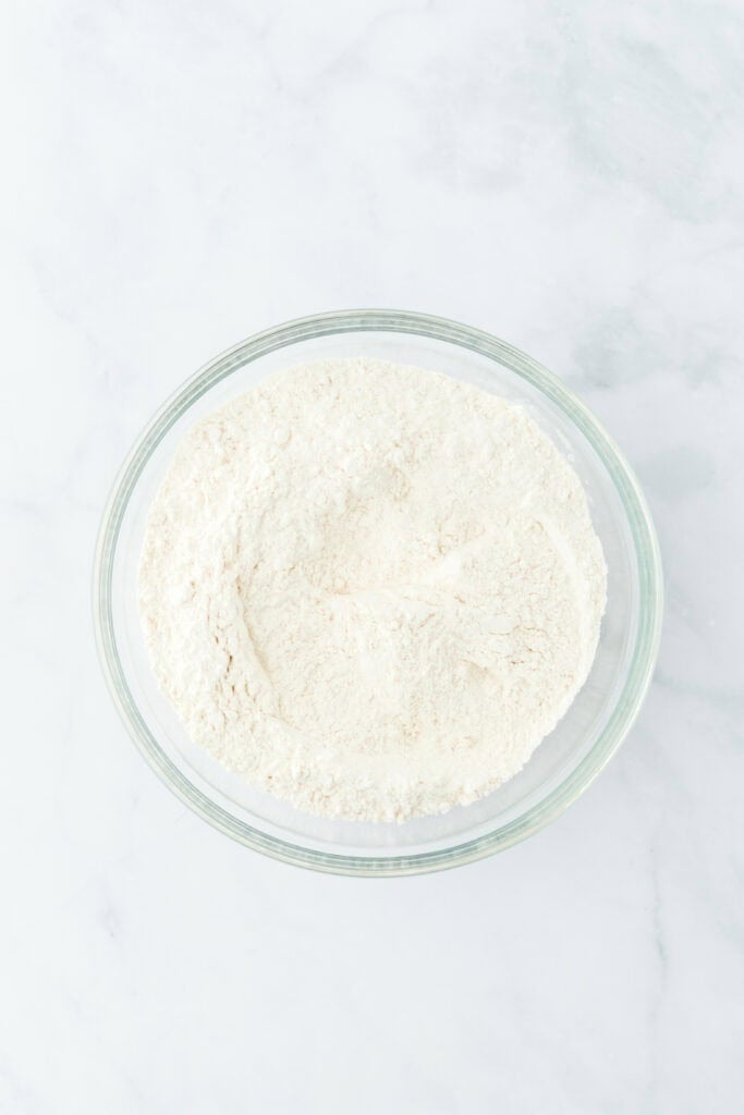 Dry ingredients stirred together in a glass bowl on white countertop