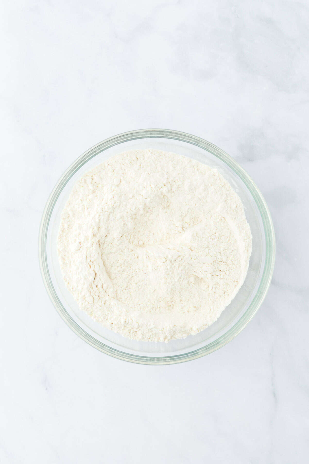 Dry ingredients stirred together in a glass bowl on white countertop