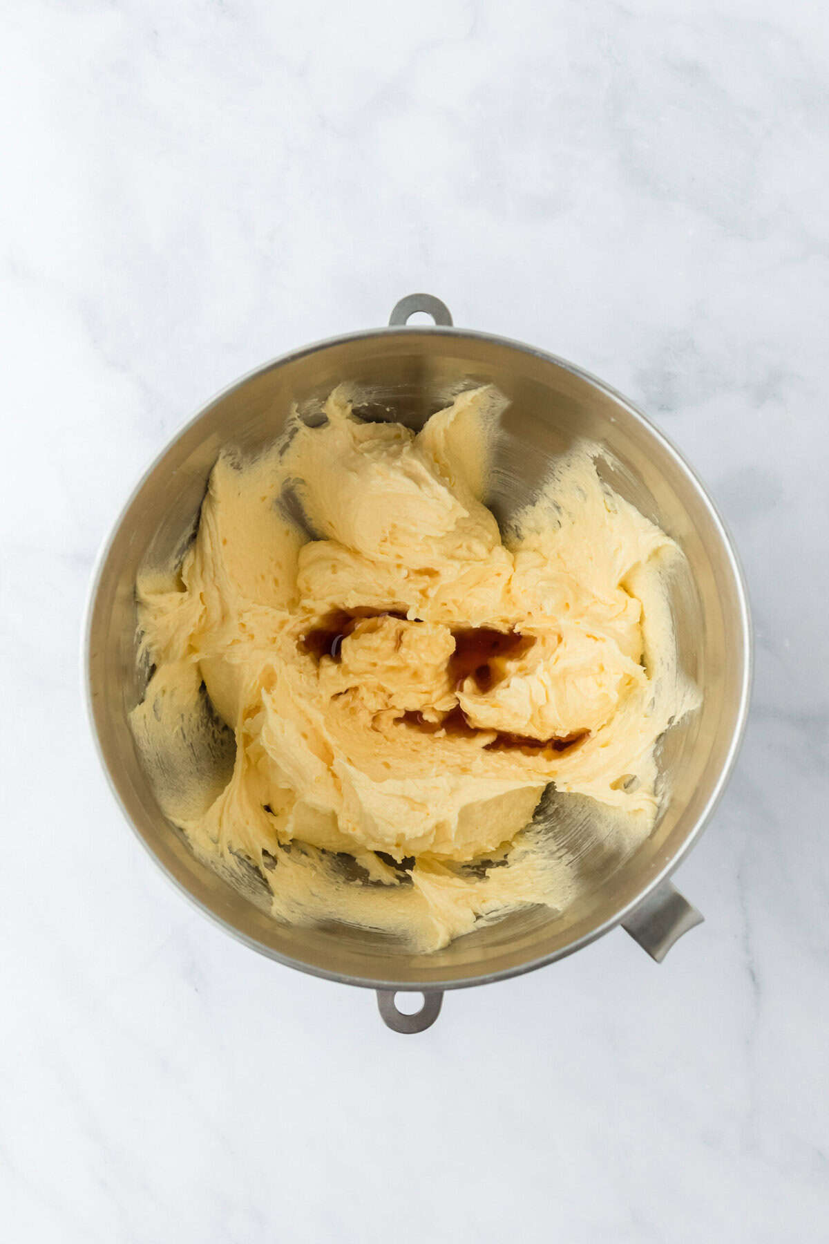 Vanilla extract added to a stand mixer bowl on white background