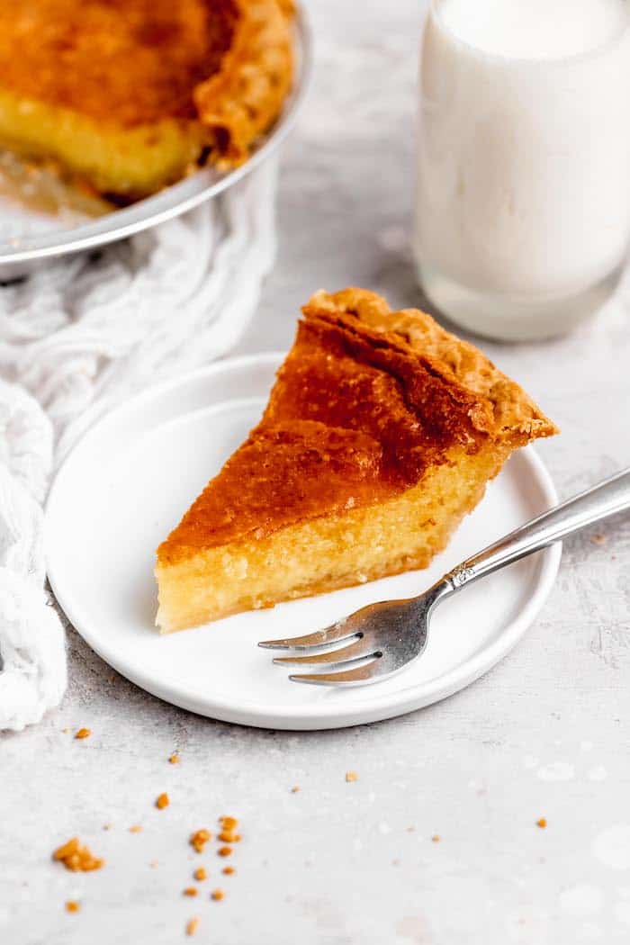 A slice of Southern custard pie sitting on a white plate with a silver fork