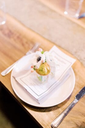 A seating at a wooden table with a flower on top of menu