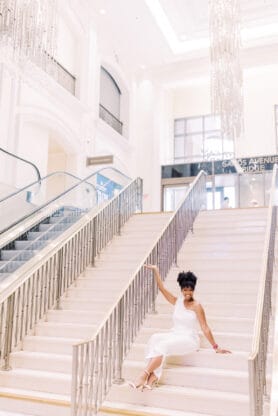 Jocelyn Delk Adams sitting on white staircase at The Palazzo in Las Vegas