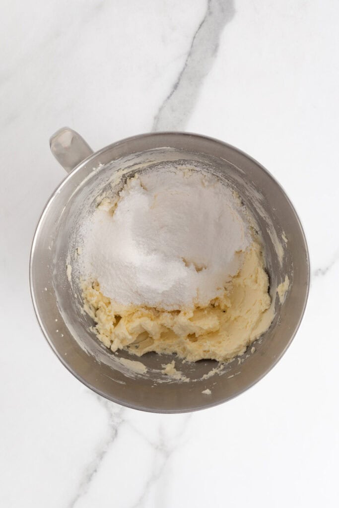 A metal mixing bowl with cream cheese, butter, and powdered sugar