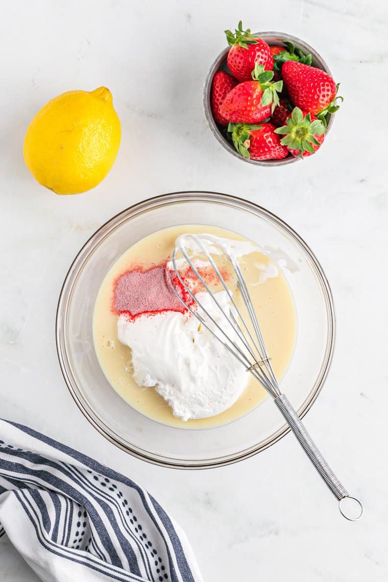 Whipped cream, sweetened condensed milk and kool-aid being whisked together in a large bowl