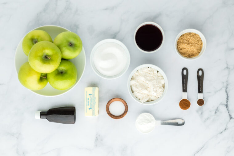 Apples, and ingredients in white bowls on white background to make a cobbler