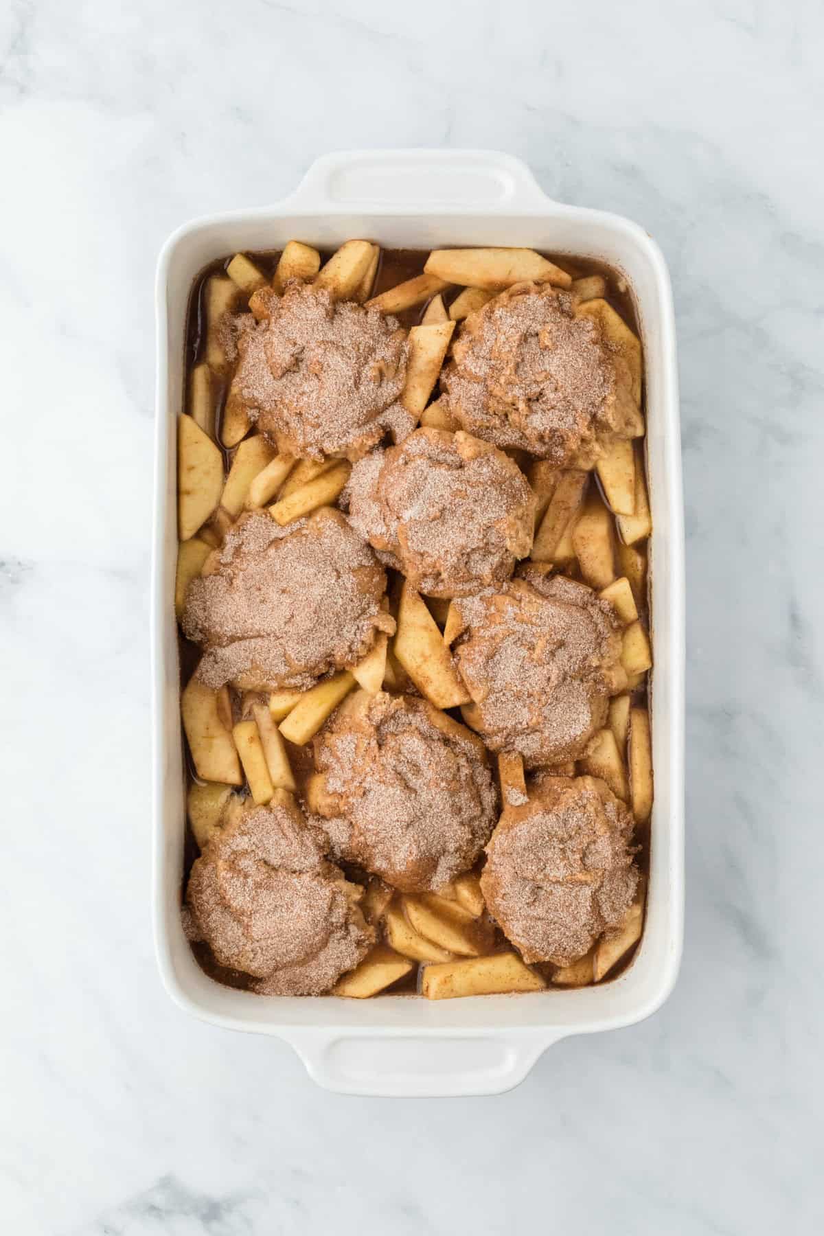 Easy apple cobbler recipe in a white baking dish on a white background before baking