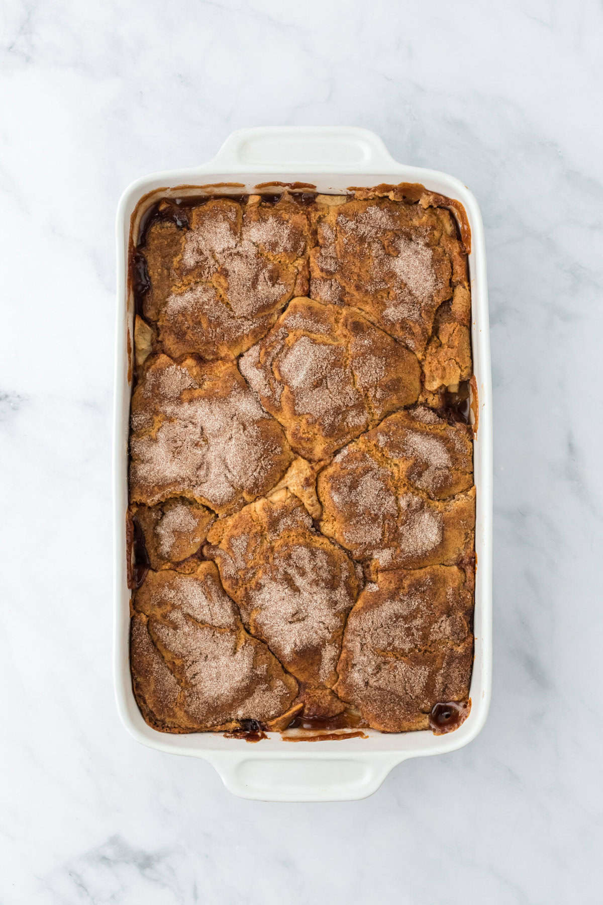 Baked apple cobbler in a white baking dish on a white background