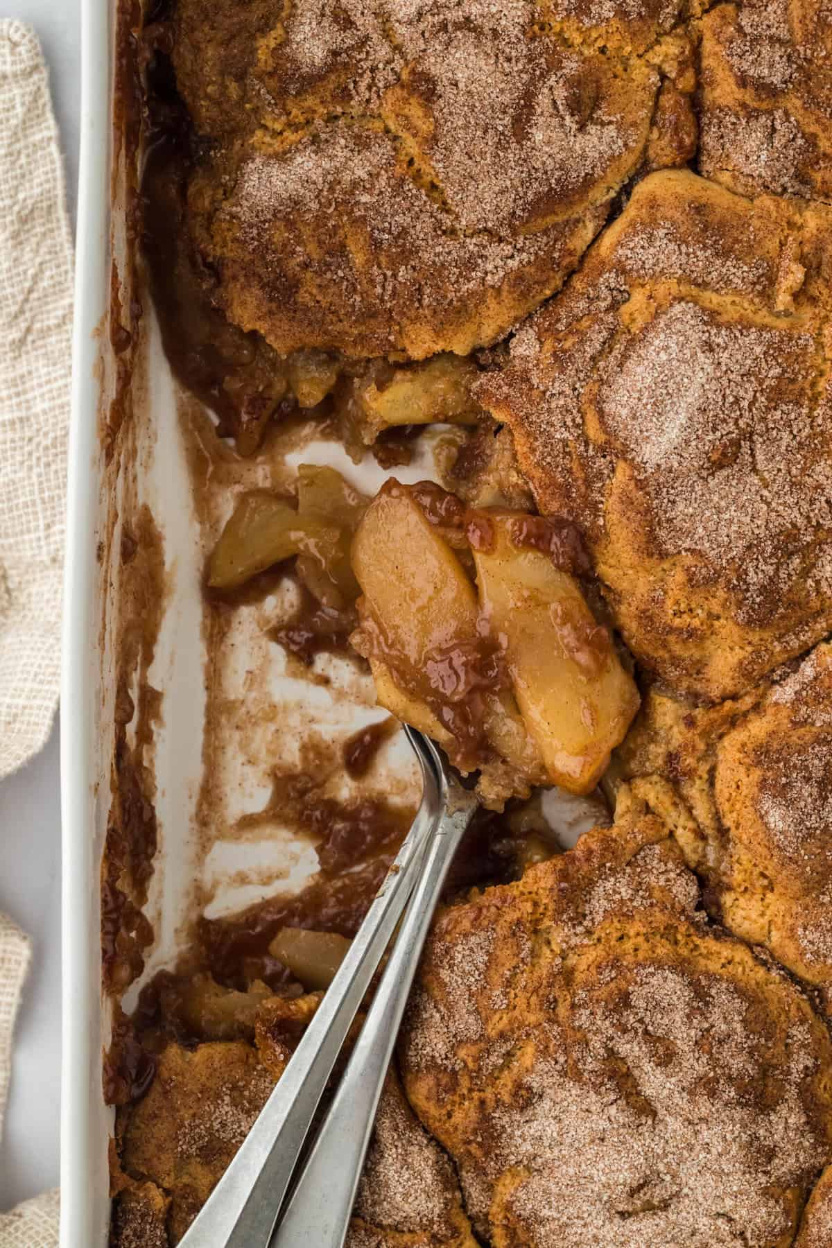 Apple cobbler recipe baked in a dish being spooned out to serve