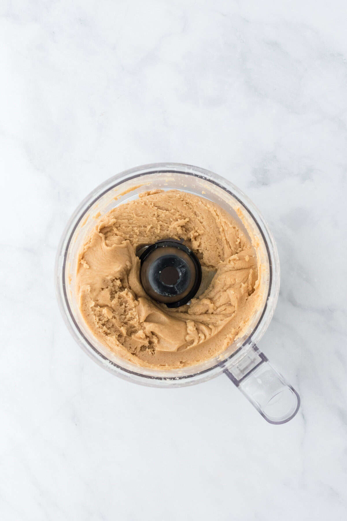 Brown sugar biscuit dough in a food processor after being combined on a white background