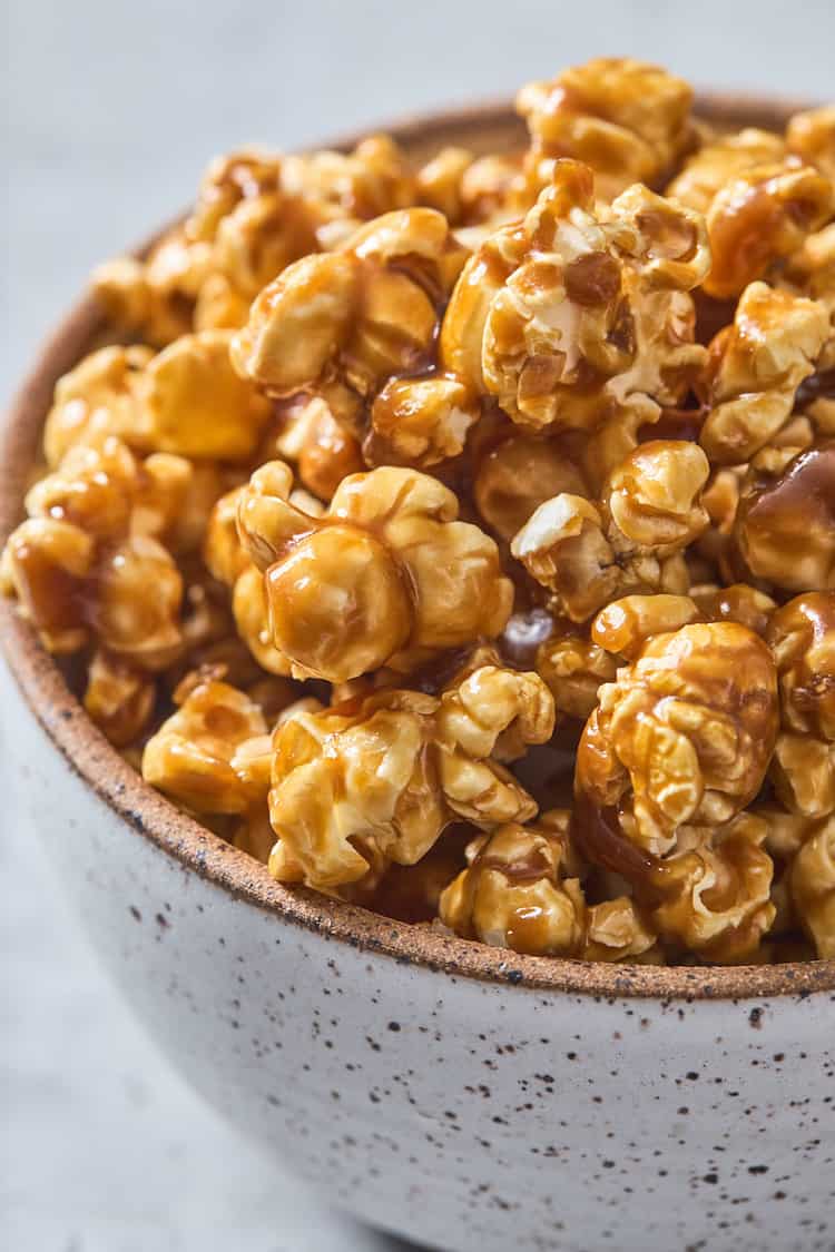 A close up of caramel corn in a gray speckled bowl ready to devour