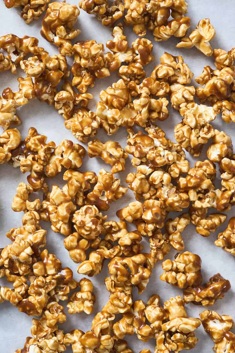 Caramel coated popcorn scattered against a white background