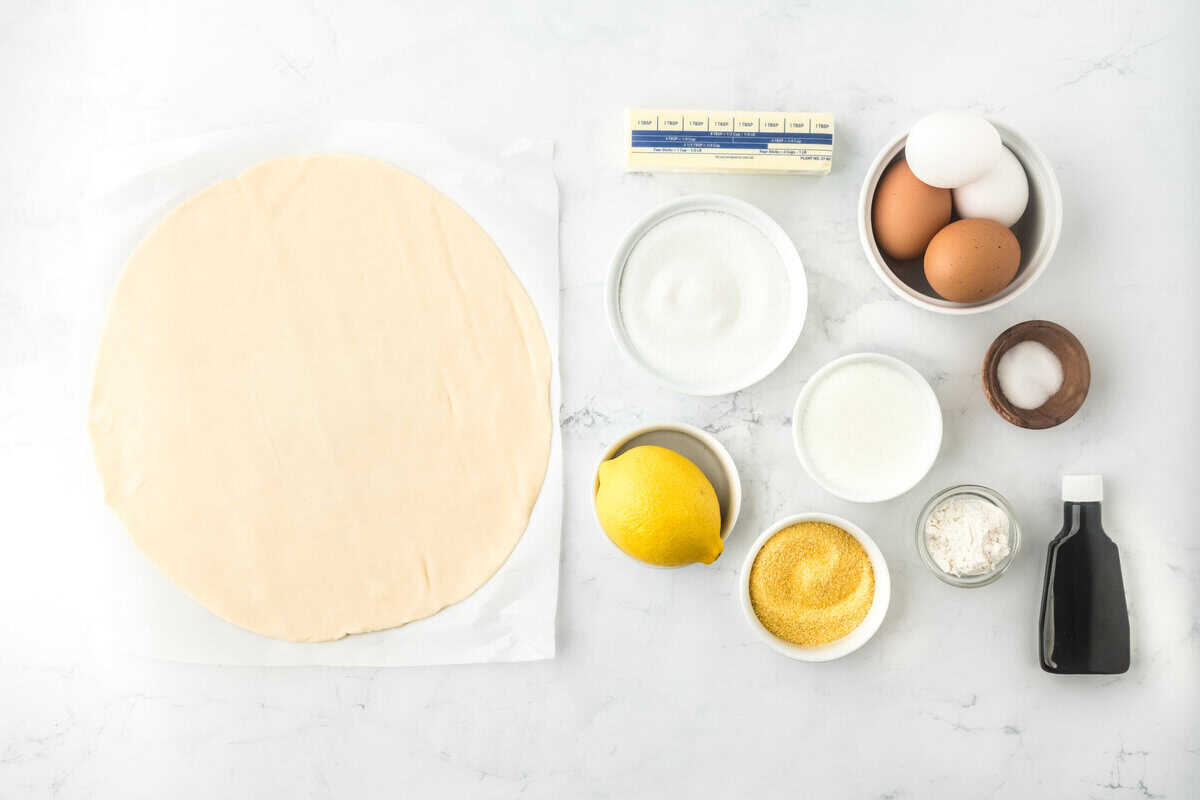 Pie dough, eggs, sugar, butter, flour, and other ingredients in white bowls to make a pie on white background