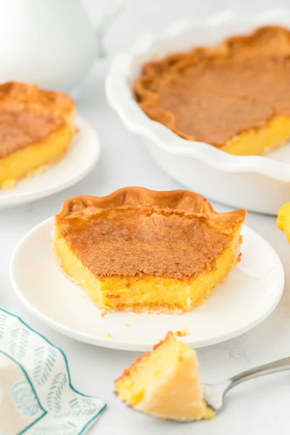 A close up of homemade chess pie recipe slice with a piece on a fork on white background