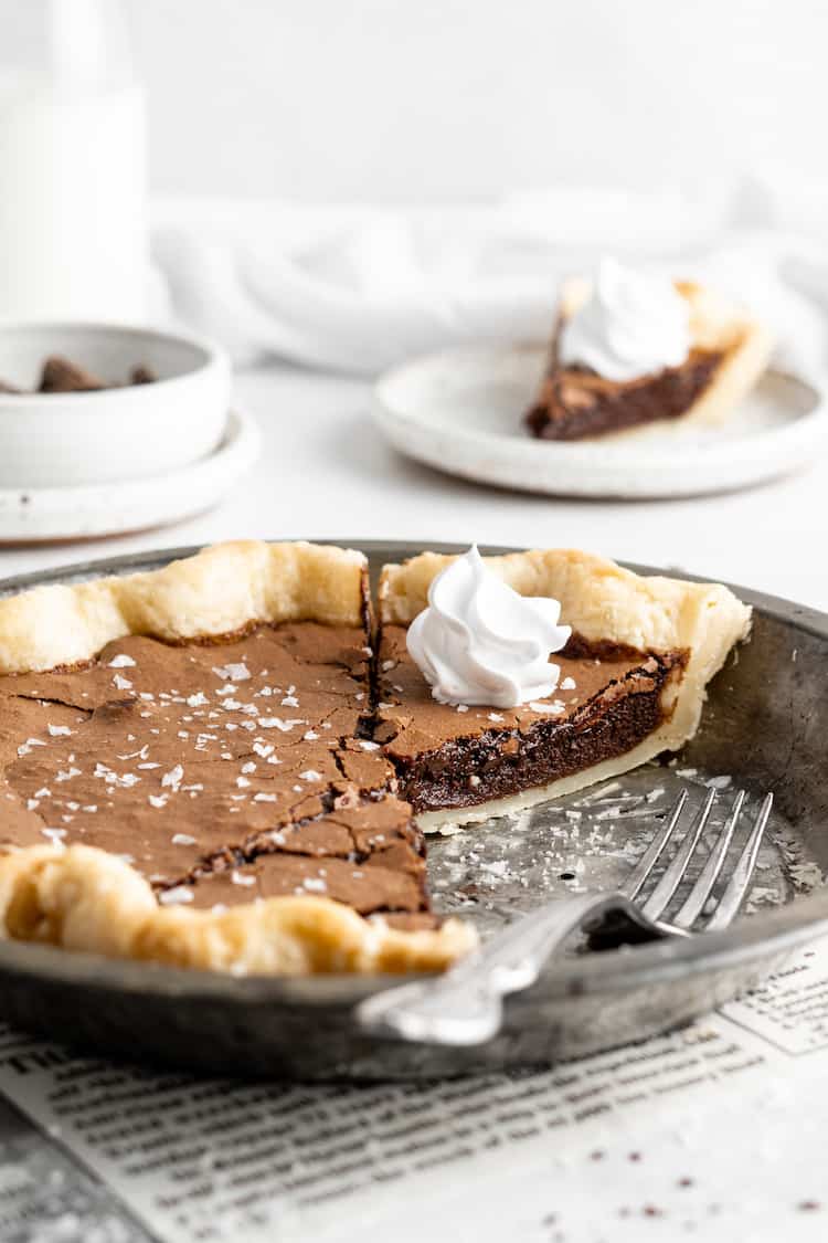 A close up of inside of a chocolate pie with a custard filling with whipped cream