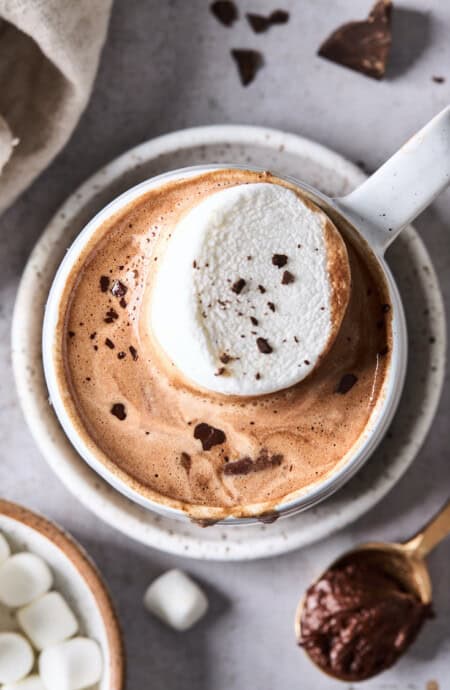 A close up of a mug of Parisian hot chocolate with a vanilla marshmallow on top and chocolate shavings