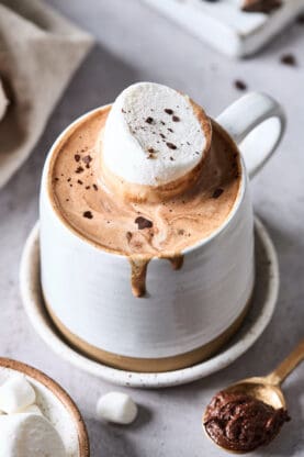 A close up of Le Chocolat Chaud with a marshmallow on top in a glass mug