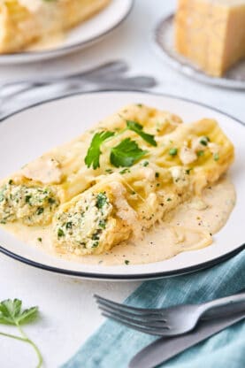 Two spinach manicotti on a white plate ready to serve
