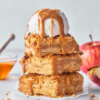 A stack of three apple bars with a scoop of vanilla ice cream and honey caramel on top