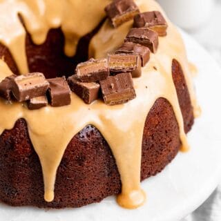 A close up of a milky way cake with a white chocolate glaze with cut up milky way bars