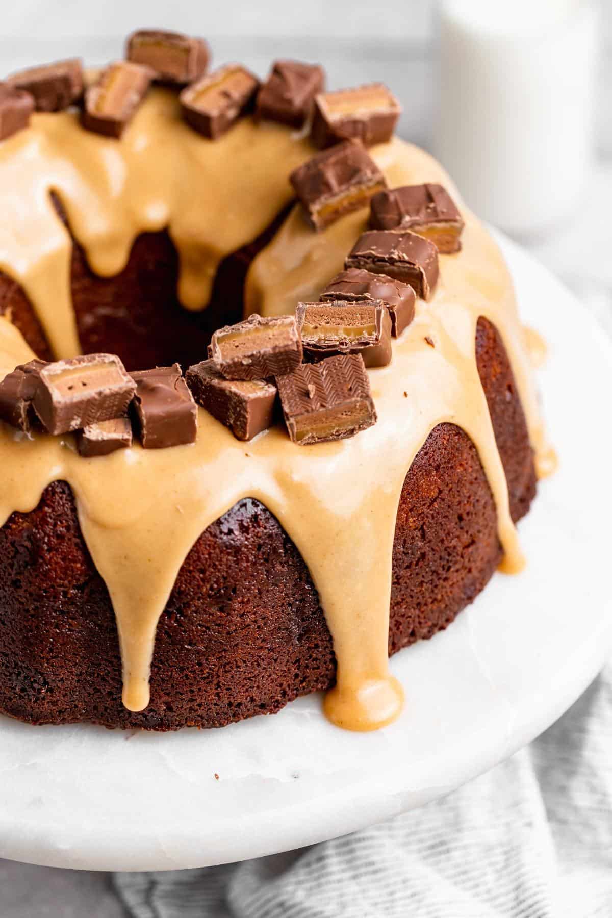 A close up of a milky way cake with a white chocolate glaze with cut up milky way bars