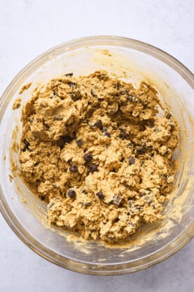 An oatmeal cookie dough with chocolate chips in a clear bowl after being mixed