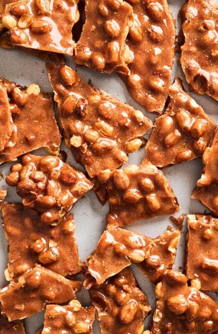 Broken up peanut brittle on the table.