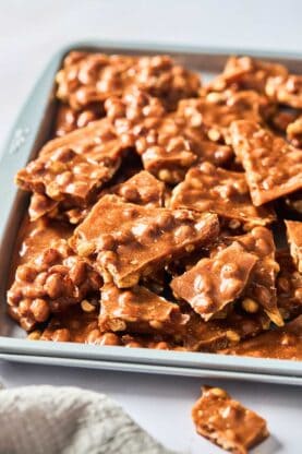 A close up of brittle on a baking sheet after being broken apart