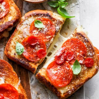 A close up of a grilled cheese with pepperoni on top with it being pulled apart