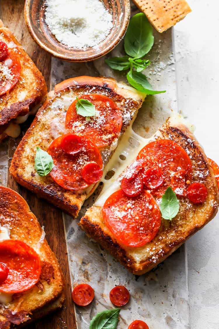 A close up of a grilled cheese with pepperoni on top with it being pulled apart