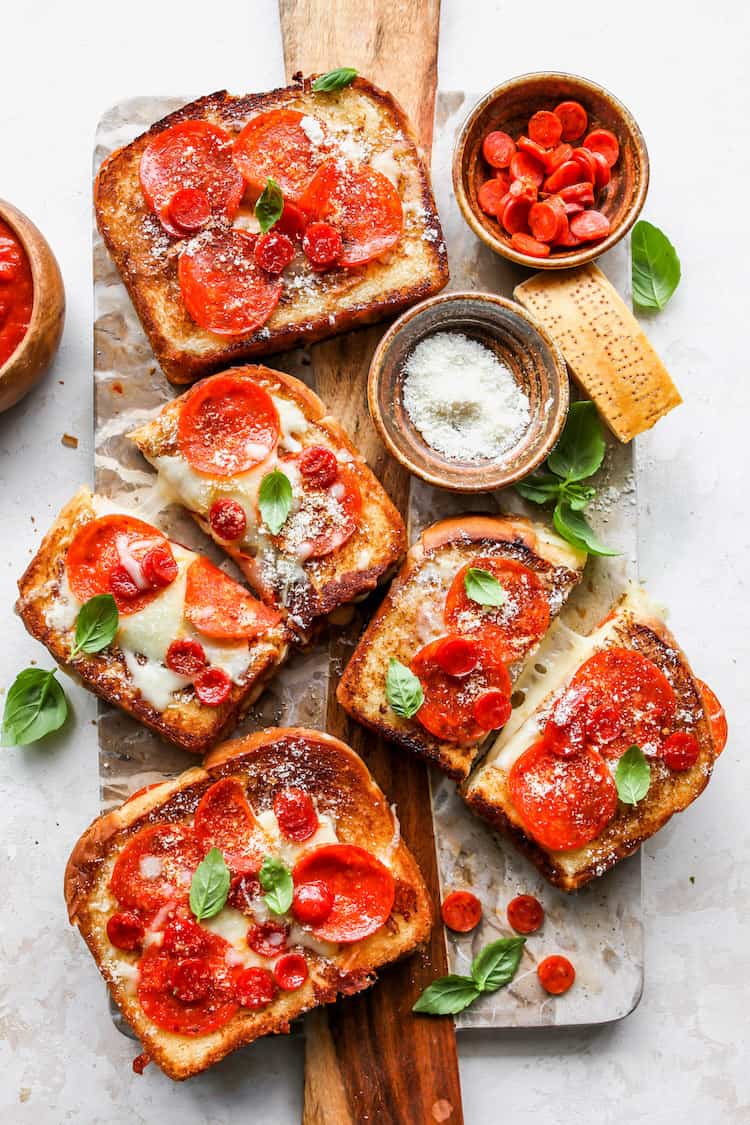 Four pizza grilled cheese sandwiches all sliced against a wood background