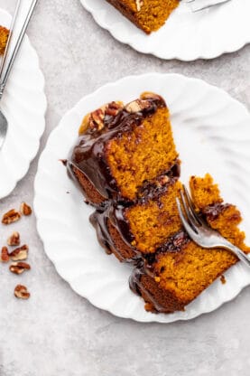 A slice of pumpkin cake with chocolate and caramel sauces and pecans with a fork slicing through