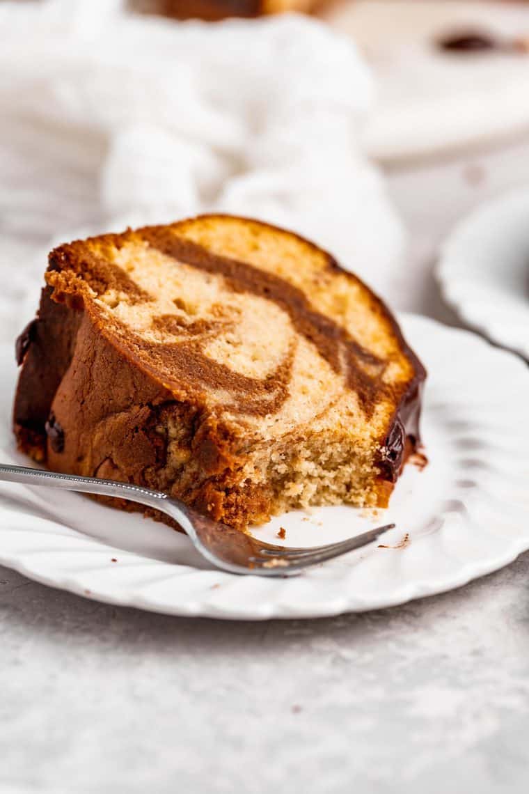 A large slice of chocolate marble cake on a white plate close up with a fork