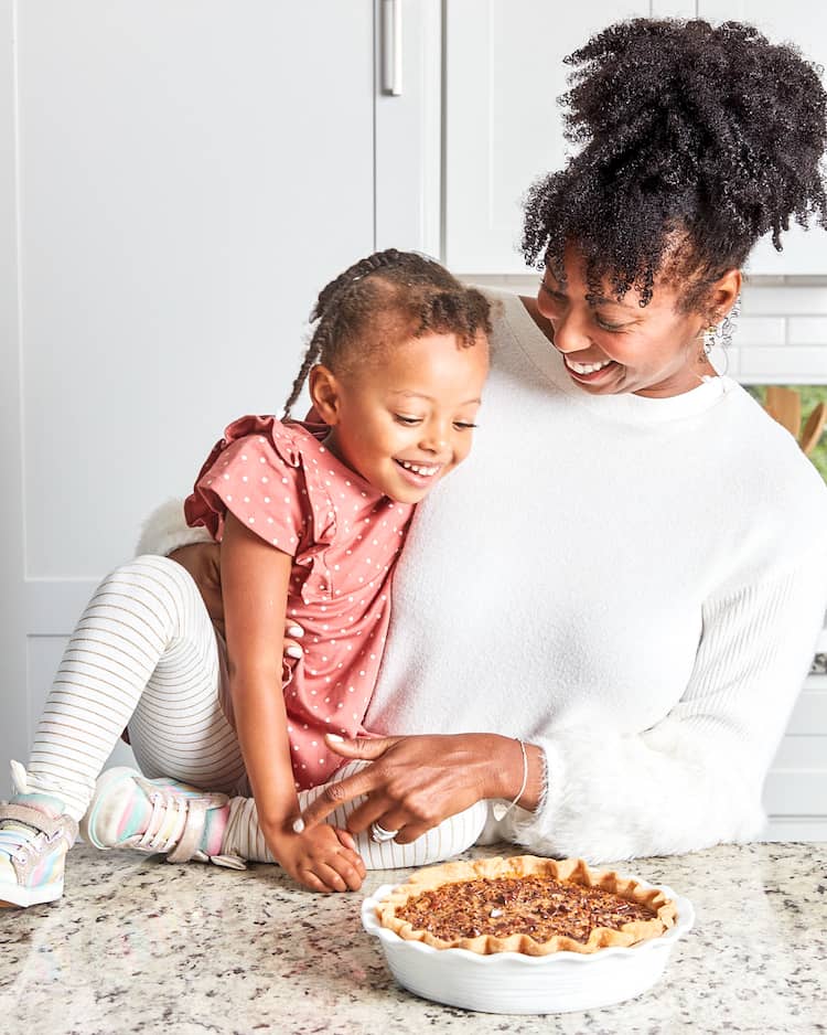 Jocelyn Delk Adams and her daughter Harmony Adams looking at a pecan pie that they baked together in a kitchen setting