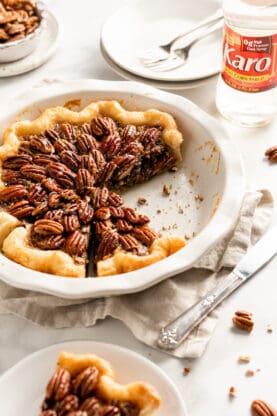 A delicious pecan pie with chocolate filling sliced with a few slices missing against white background