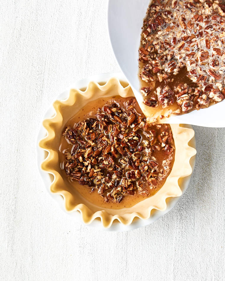 Chocolate bourbon pecan filling being poured into a pie dough