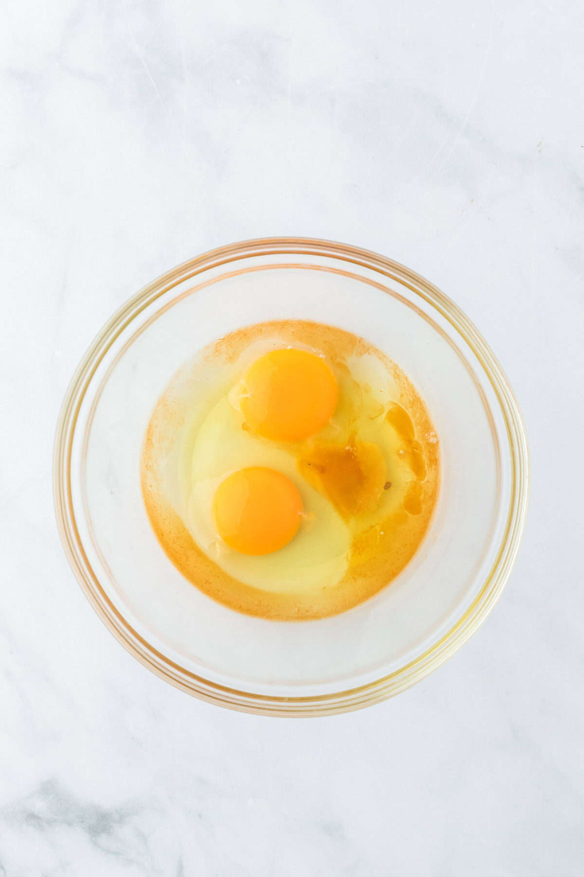 Eggs, vanilla and salt in a glass bowl on white countertop