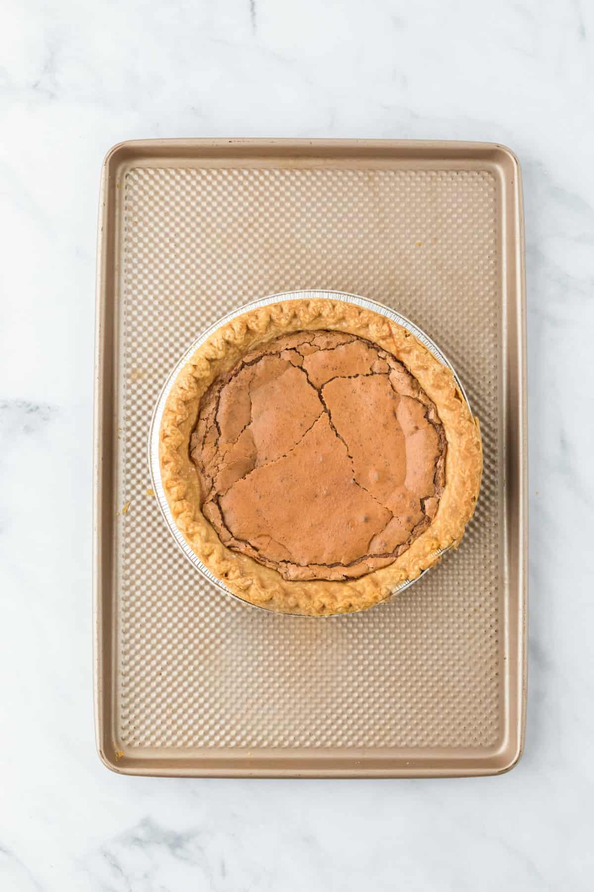 Chocolate chess pie after being baked on baking sheet on white countertop