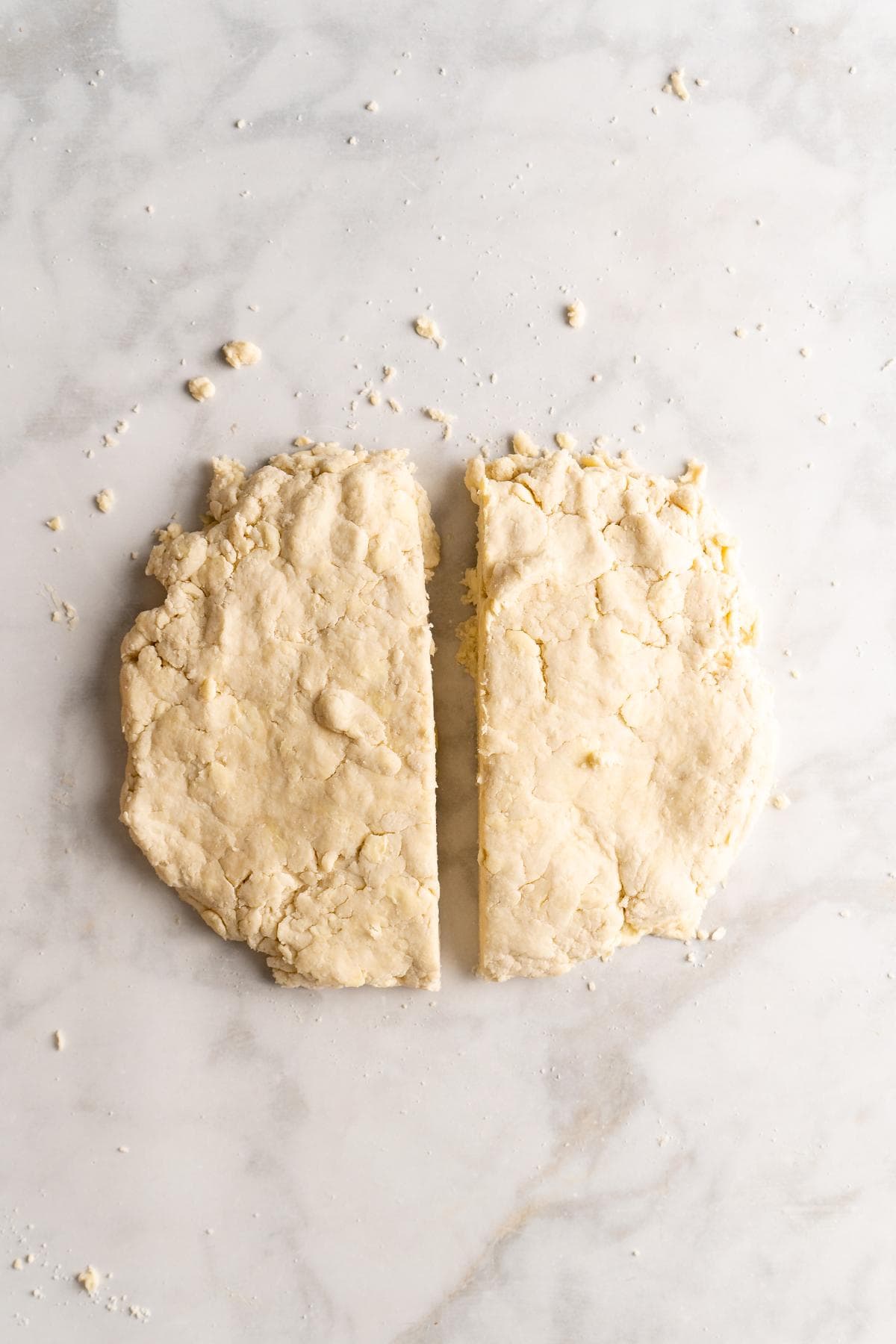 Biscuit dough cut in half lengthwise on a marble surface