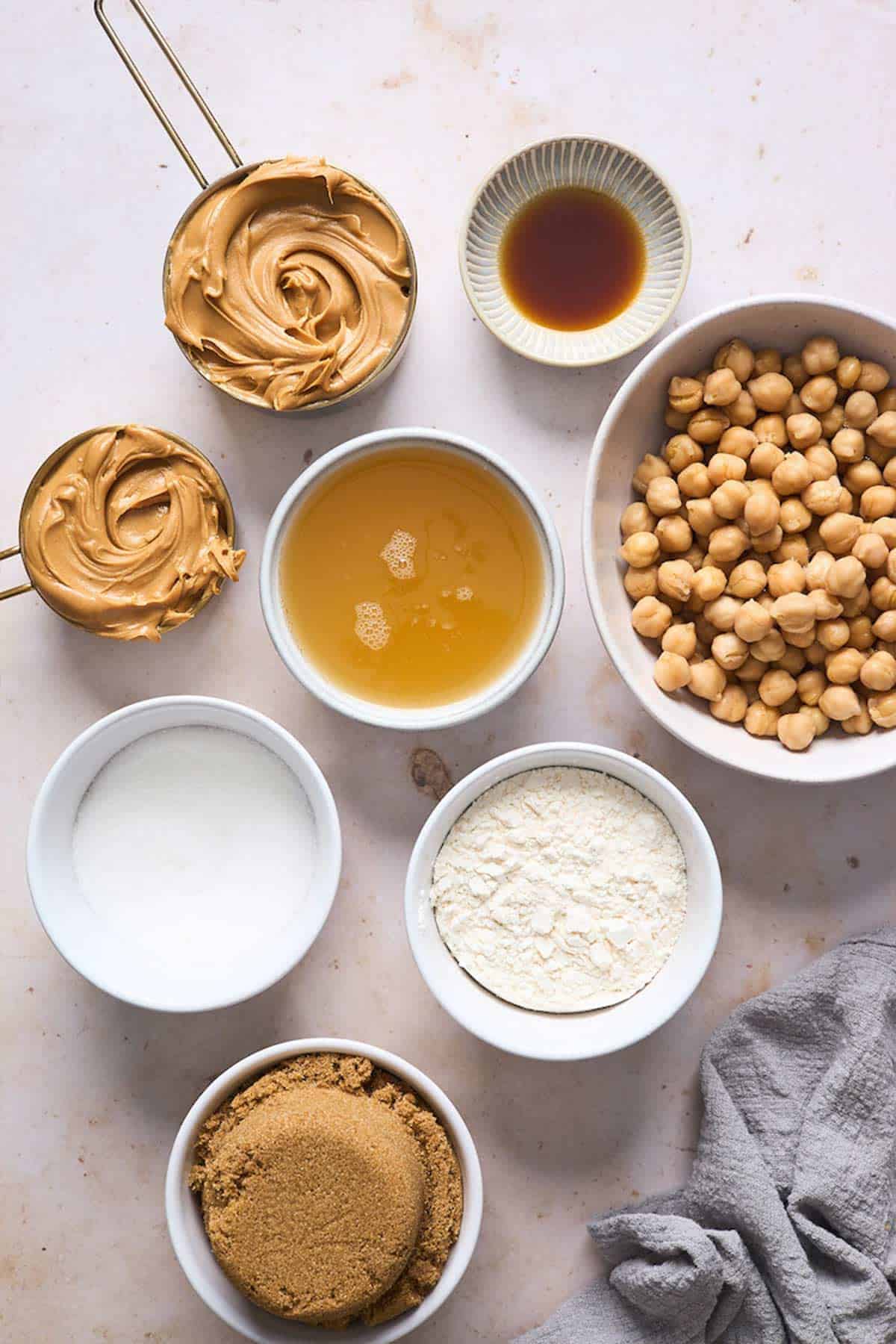 Ingredients in white bowls to bake healthy chickpea cookies.