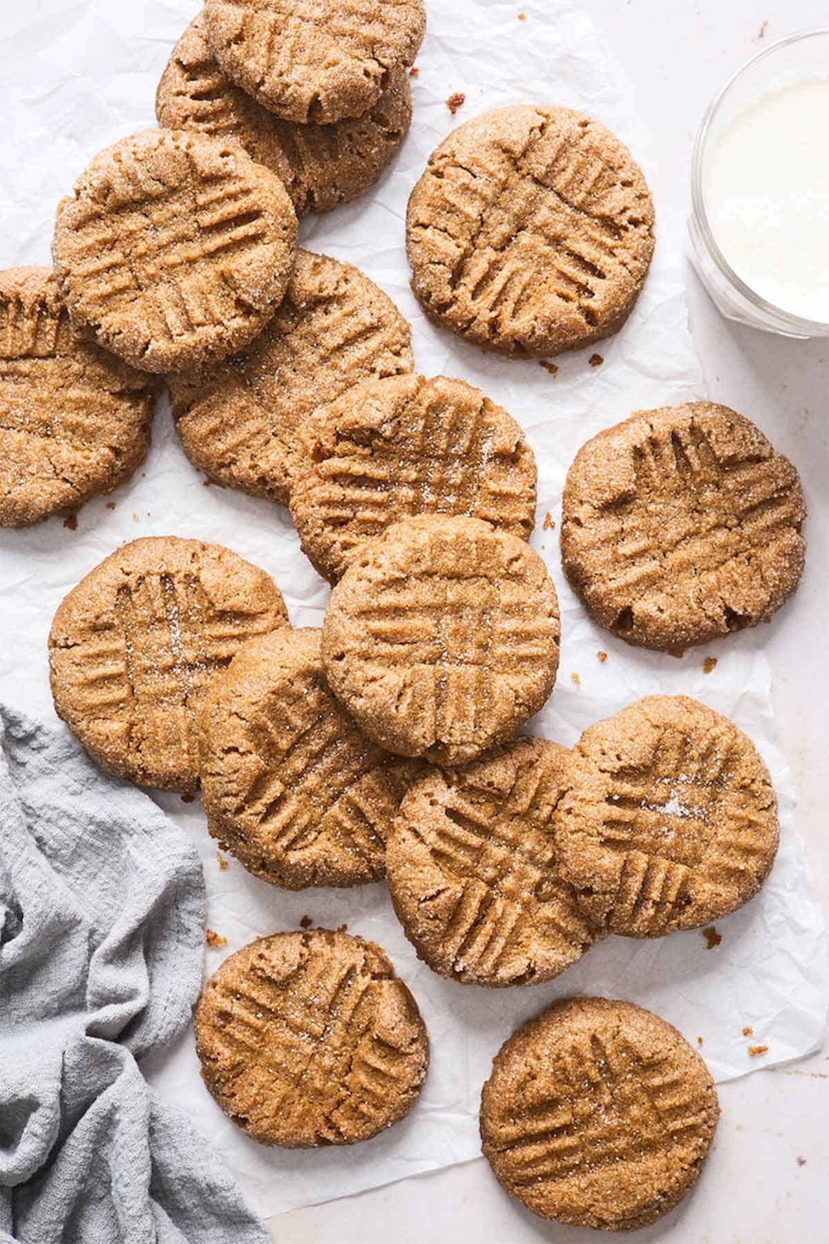 Fresh peanut butter chickpea cookies scattered against white background with a gray towel.