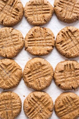 Fresh peanut butter cookies scattered against white background 