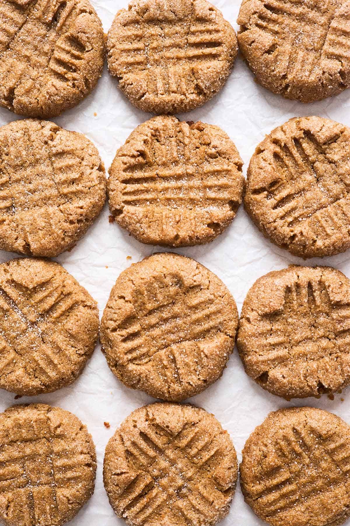 Fresh peanut butter cookies scattered against white background